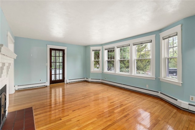 unfurnished living room featuring hardwood / wood-style floors, a baseboard heating unit, a fireplace, and baseboard heating