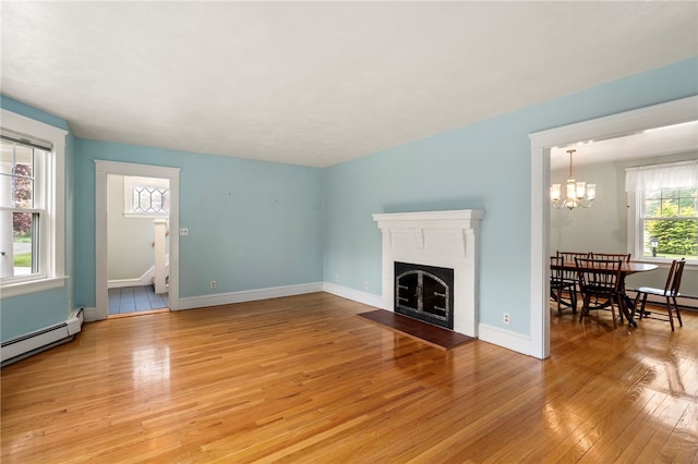 unfurnished living room featuring light wood finished floors, a chandelier, a fireplace with flush hearth, stairs, and baseboards