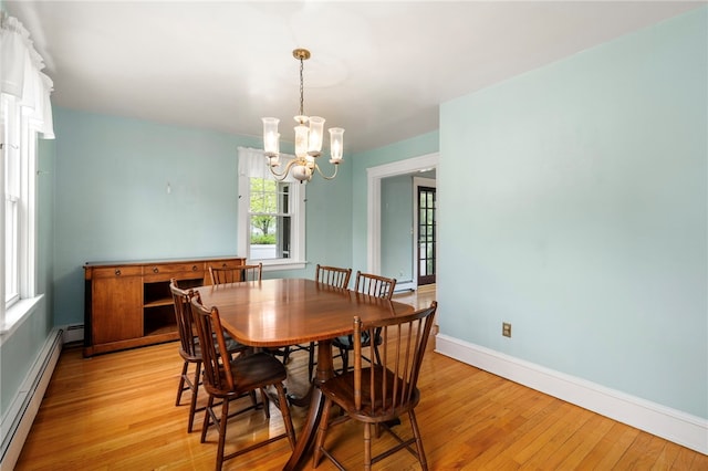 dining space with a chandelier, light wood finished floors, baseboard heating, and baseboards
