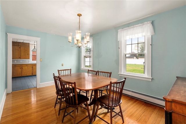 dining space with baseboard heating, light wood-style floors, a chandelier, and baseboards