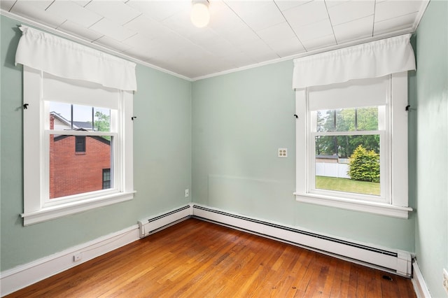 spare room with plenty of natural light, hardwood / wood-style floors, ornamental molding, and a baseboard heating unit