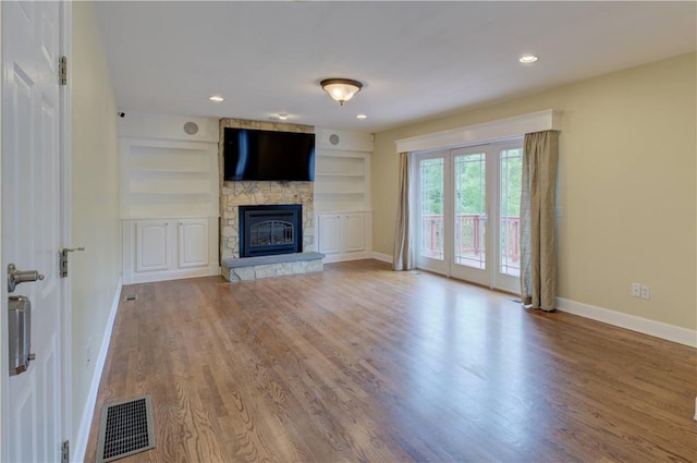 34 Ledgefield Rd, Scituate, RI 02857 - unfurnished living room featuring baseboards, a stone fireplace, wood finished floors, and built in shelves
