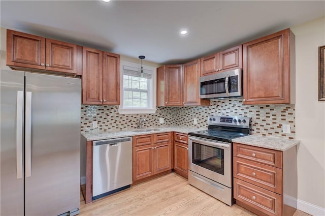 34 Ledgefield Rd, Scituate, RI 02857 - kitchen featuring appliances with stainless steel finishes, brown cabinetry, light wood-style flooring, decorative backsplash, and recessed lighting