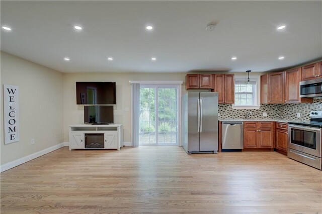 34 Ledgefield Rd, Scituate, RI 02857 - kitchen with stainless steel appliances, light wood-type flooring, tasteful backsplash, baseboards, and brown cabinetry