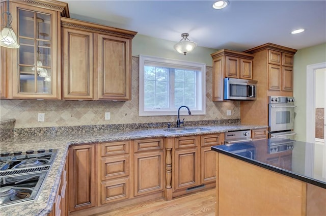 34 Ledgefield Rd, Scituate, RI 02857 - kitchen featuring a sink, stainless steel appliances, brown cabinetry, tasteful backsplash, and glass insert cabinets