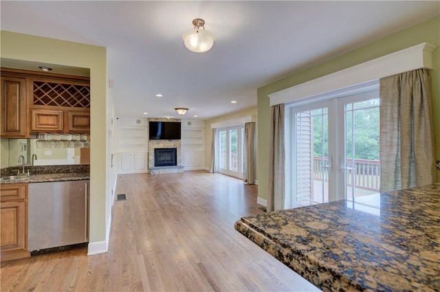 34 Ledgefield Rd, Scituate, RI 02857 - kitchen with a sink, dishwasher, light wood-style floors, brown cabinets, and a glass covered fireplace