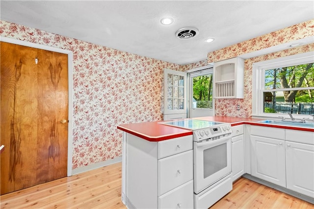 54 Glenwood Dr, North Kingstown, RI 02852 - kitchen with white electric range oven, a sink, wallpapered walls, light wood-type flooring, and a peninsula