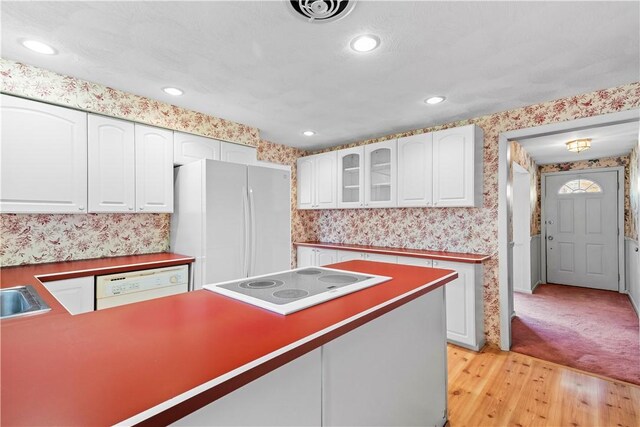 54 Glenwood Dr, North Kingstown, RI 02852 - kitchen with wallpapered walls, white appliances, light wood finished floors, white cabinetry, and glass insert cabinets