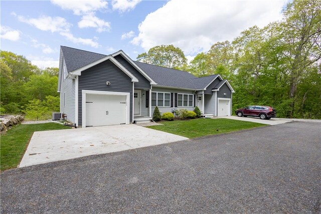 single story home featuring an attached garage, a front yard, concrete driveway, and central air condition unit