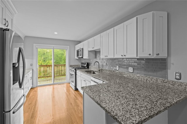 kitchen featuring appliances with stainless steel finishes, a sink, white cabinetry, tasteful backsplash, and recessed lighting