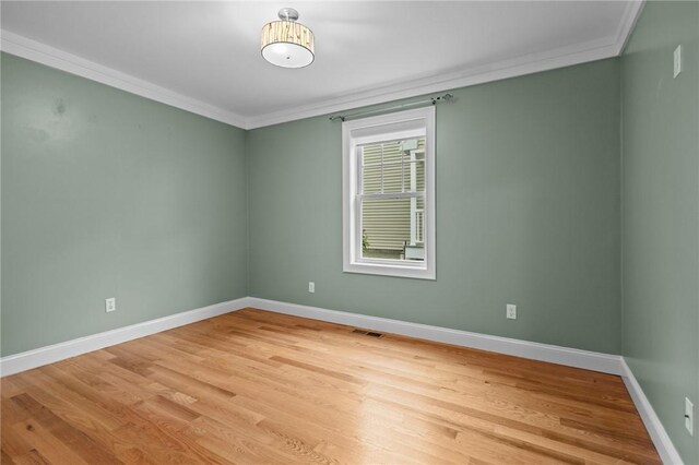 unfurnished room with crown molding, light wood-style flooring, and baseboards