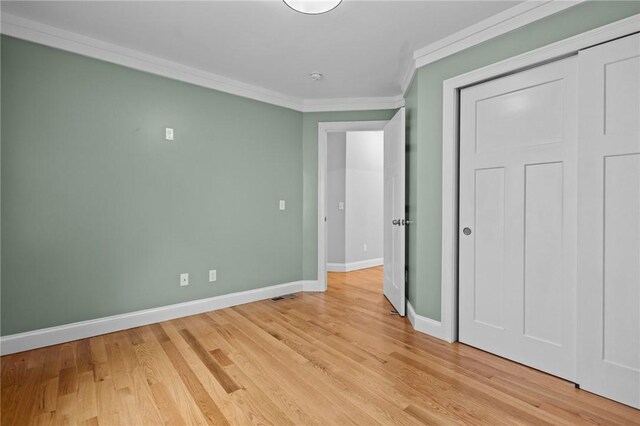 unfurnished bedroom featuring ornamental molding, baseboards, light wood finished floors, and a closet