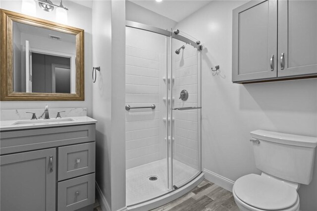full bath with baseboards, wood finished floors, toilet, and a stall shower