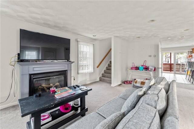 carpeted living area featuring healthy amount of natural light, stairway, a glass covered fireplace, baseboards, and recessed lighting