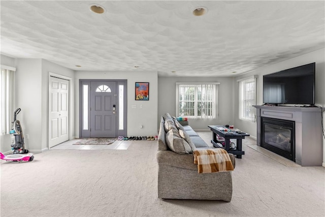 carpeted living room featuring a glass covered fireplace and baseboards