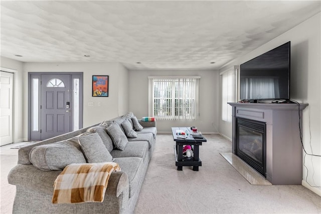 living area with a glass covered fireplace, light carpet, and baseboards