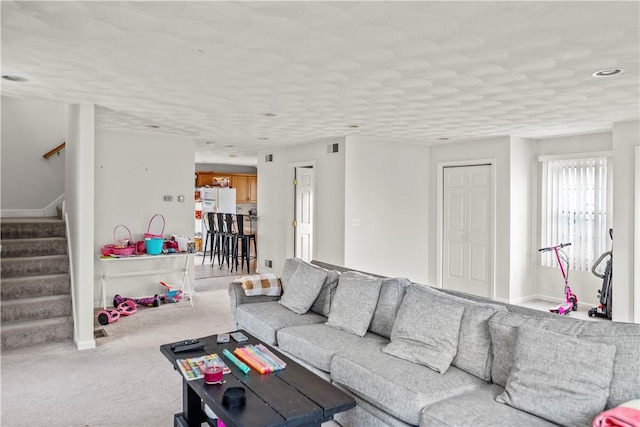 carpeted living area with stairway and baseboards