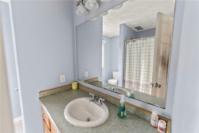 bathroom featuring toilet, vanity, and curtained shower