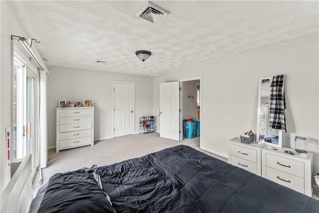 bedroom with light colored carpet, a textured ceiling, and baseboards