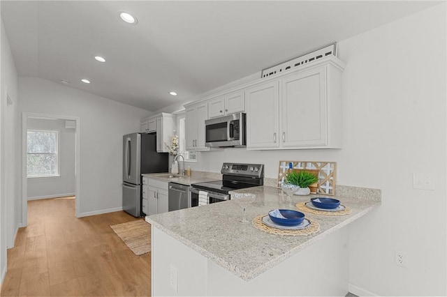 kitchen featuring appliances with stainless steel finishes, a sink, recessed lighting, light wood-style flooring, and baseboards