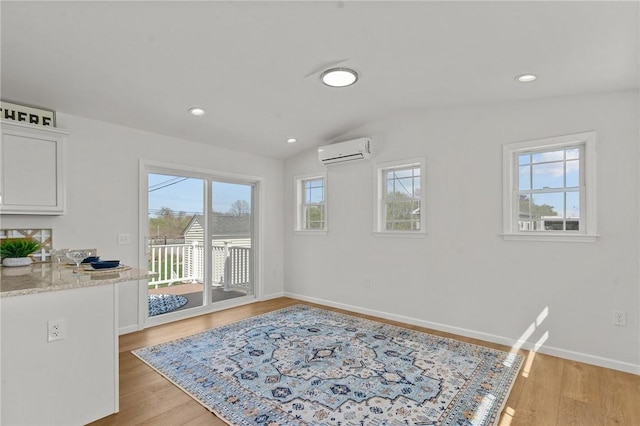 dining space featuring a wall mounted air conditioner, plenty of natural light, vaulted ceiling, light wood-type flooring, and recessed lighting