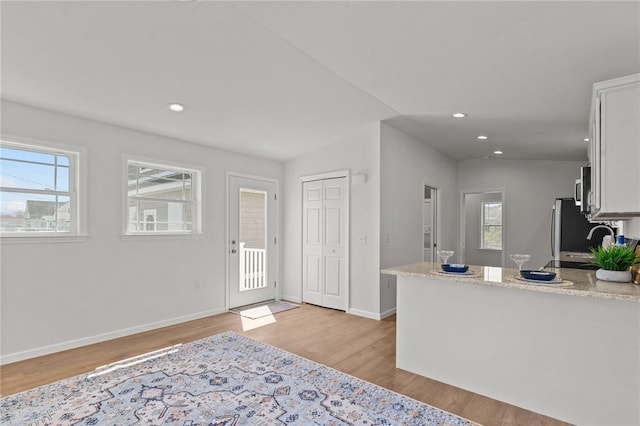 foyer entrance with light wood finished floors, plenty of natural light, baseboards, and recessed lighting