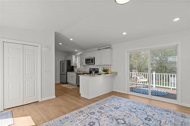 kitchen with stainless steel appliances, white cabinets, light wood-type flooring, baseboards, and light countertops