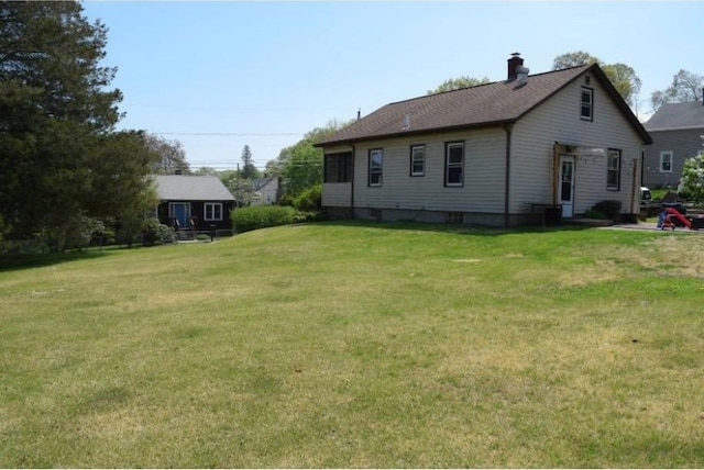back of house with a yard and a chimney
