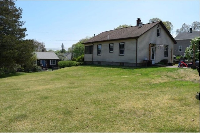 back of property featuring a chimney and a lawn