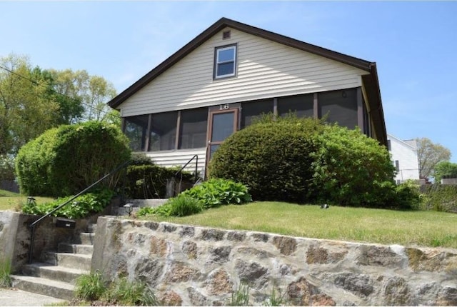 view of front of property with a sunroom, stairs, and a front lawn