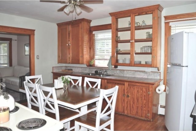 kitchen with freestanding refrigerator, a sink, brown cabinetry, ceiling fan, and plenty of natural light
