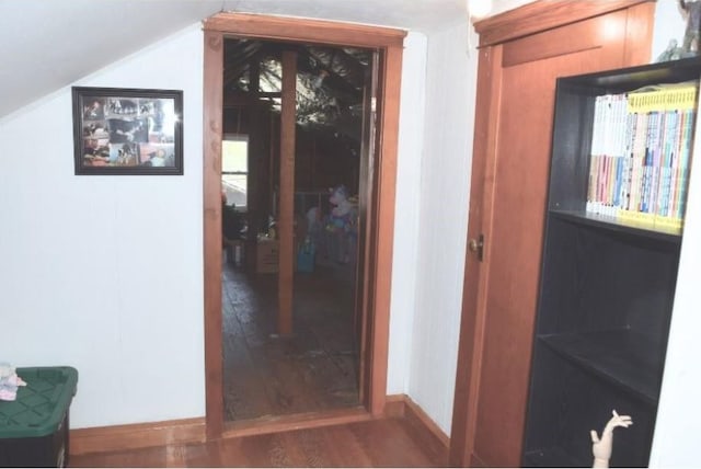 hall featuring lofted ceiling, baseboards, and wood finished floors