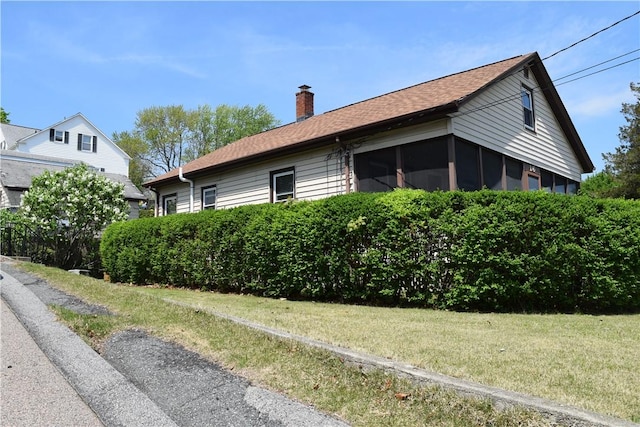 view of home's exterior featuring a chimney, a yard, and roof with shingles