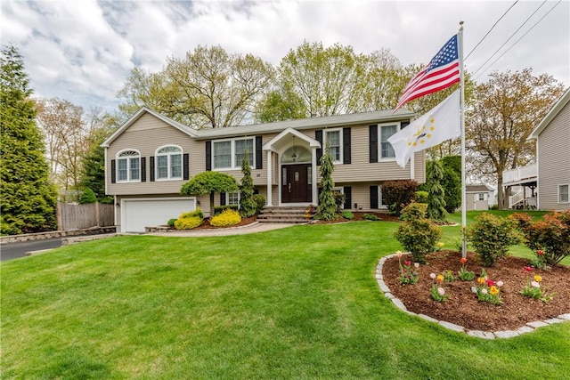 bi-level home featuring a garage, a front lawn, and driveway