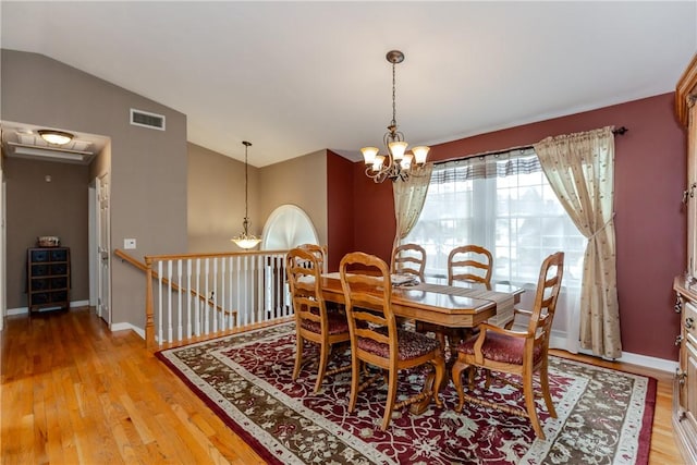 dining area with a chandelier, lofted ceiling, light wood-style floors, and baseboards