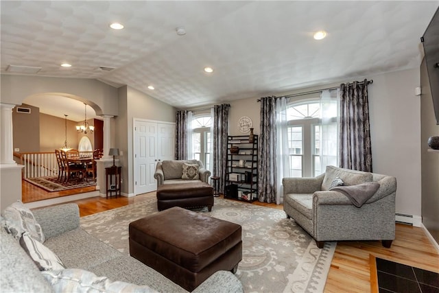 living area with decorative columns, arched walkways, a baseboard heating unit, wood finished floors, and lofted ceiling