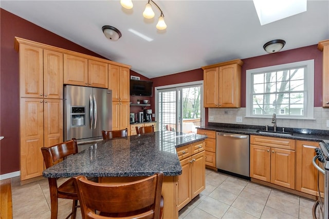 kitchen with appliances with stainless steel finishes, a sink, lofted ceiling, decorative backsplash, and a breakfast bar