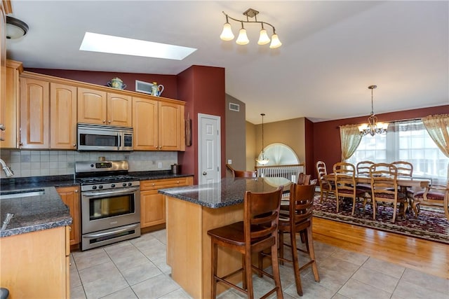 kitchen with stainless steel appliances, a chandelier, vaulted ceiling, a sink, and light tile patterned floors