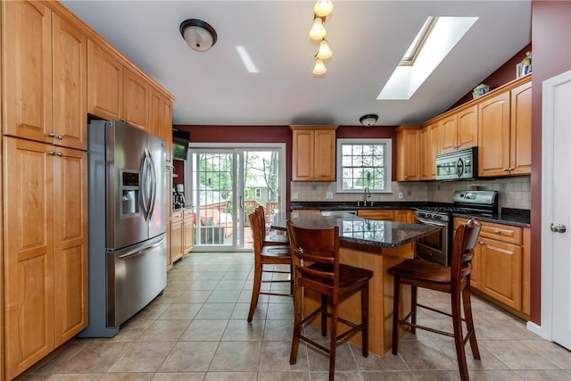 kitchen featuring appliances with stainless steel finishes, a sink, tasteful backsplash, and a skylight