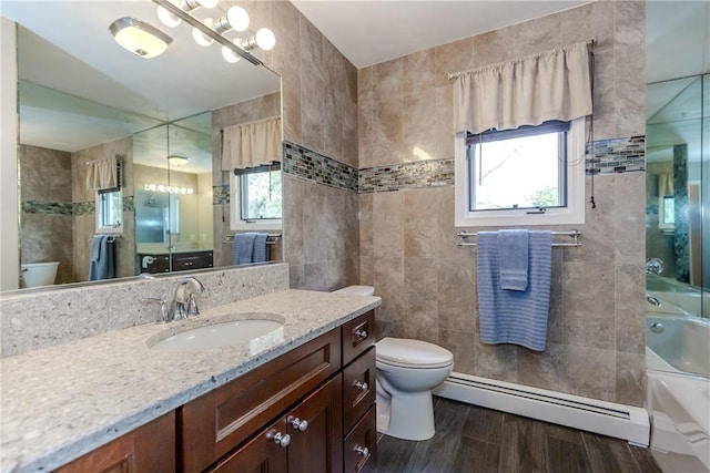 full bathroom with baseboard heating, toilet, healthy amount of natural light, vanity, and tile walls