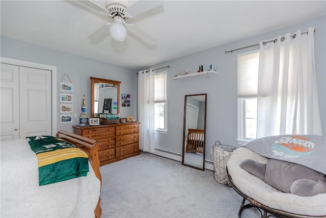 bedroom with light colored carpet, a closet, a baseboard heating unit, and ceiling fan