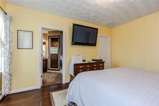 bedroom with dark wood finished floors, baseboards, and washer / dryer
