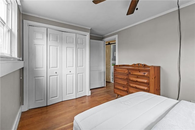 bedroom with wood finished floors, ornamental molding, baseboards, a closet, and ceiling fan