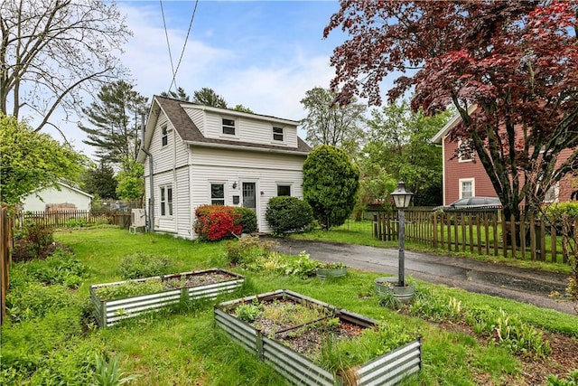 rear view of house featuring a garden and a shingled roof