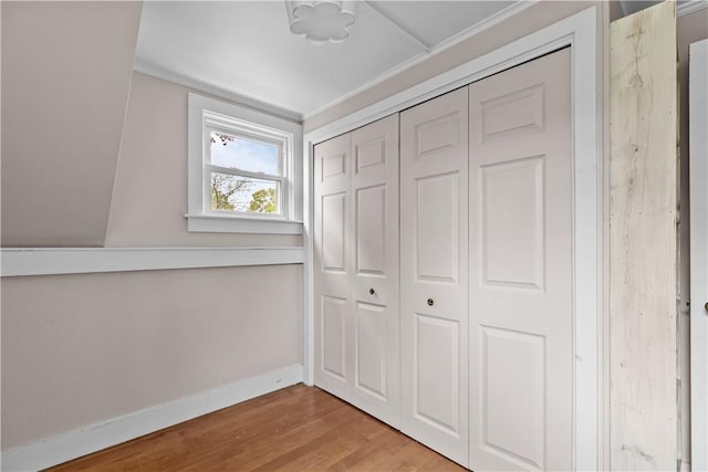 unfurnished bedroom featuring wood finished floors, a closet, and baseboards