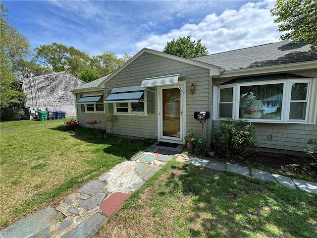 bungalow with a front lawn and roof with shingles