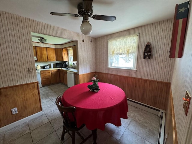 dining area with wallpapered walls, a wainscoted wall, light tile patterned floors, a ceiling fan, and wooden walls