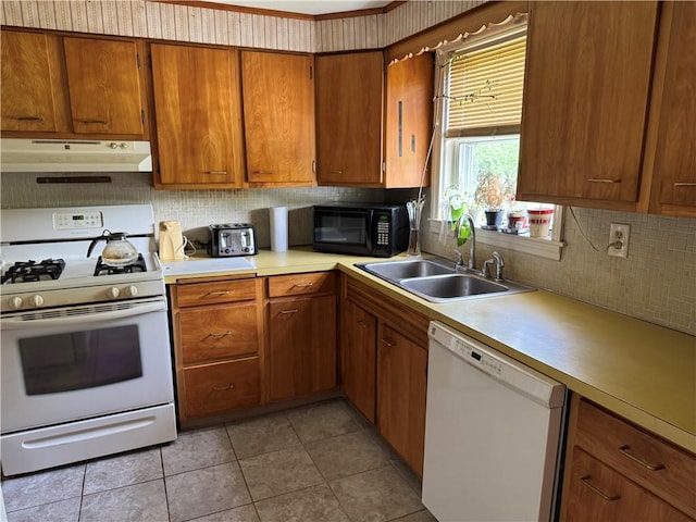 kitchen with white appliances, under cabinet range hood, a sink, and decorative backsplash