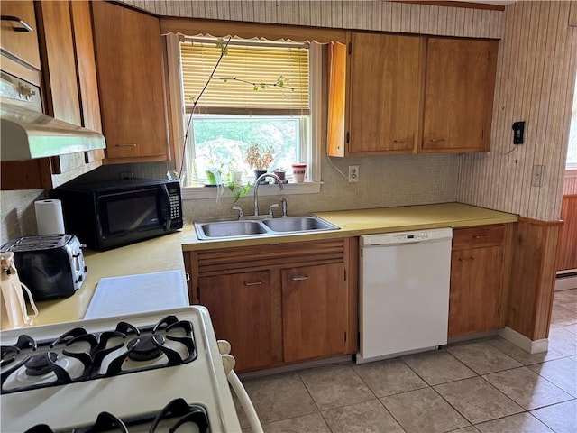 kitchen with white appliances, a sink, light countertops, and brown cabinetry