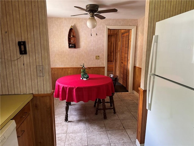 dining area featuring wallpapered walls, a wainscoted wall, and a ceiling fan